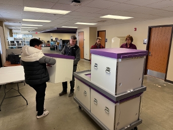 people loading mobile lab boxes onto cart in warehouse